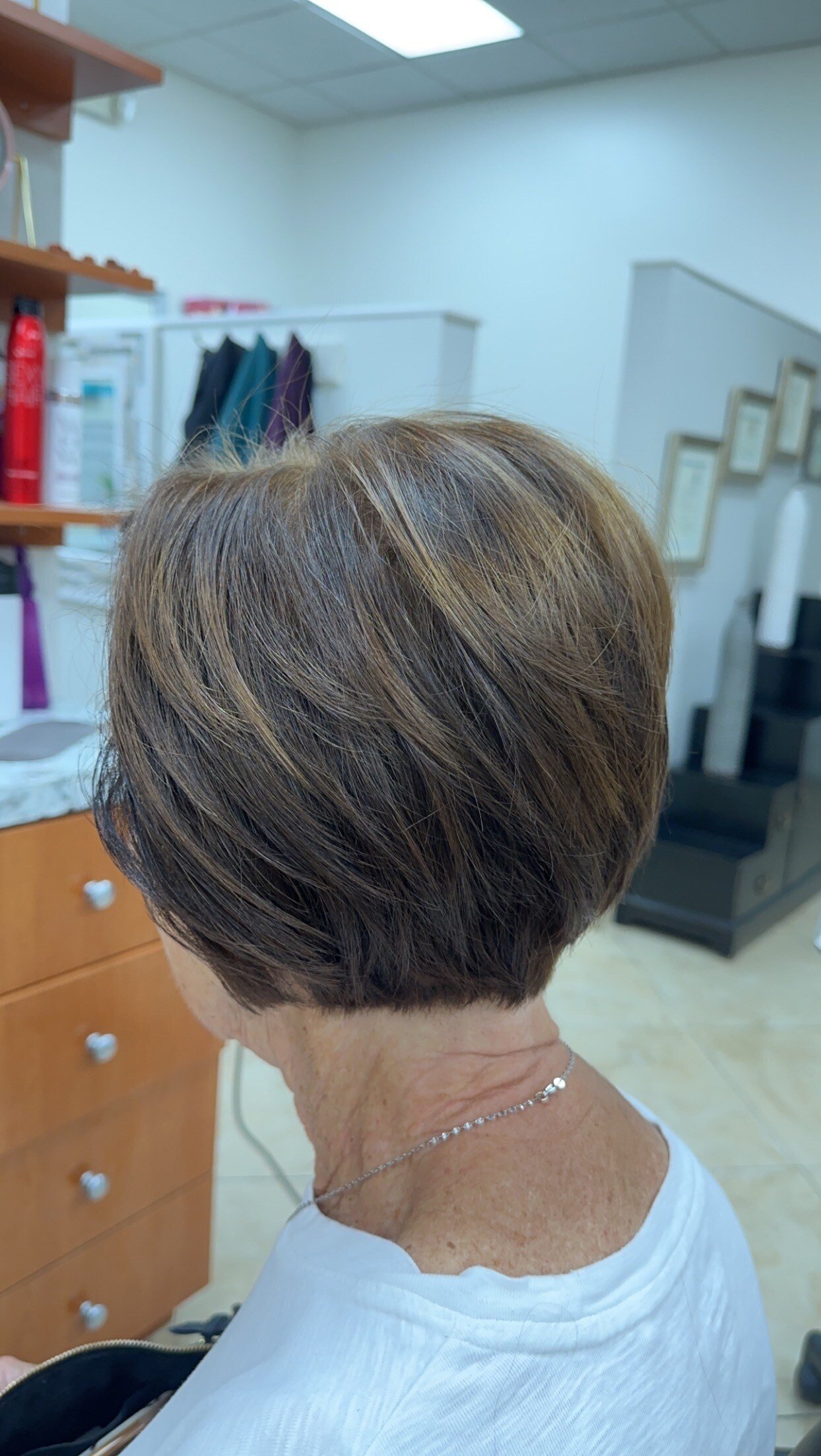 “Short, layered haircut with soft brown tones and subtle highlights, styled neatly, photographed in a salon.”