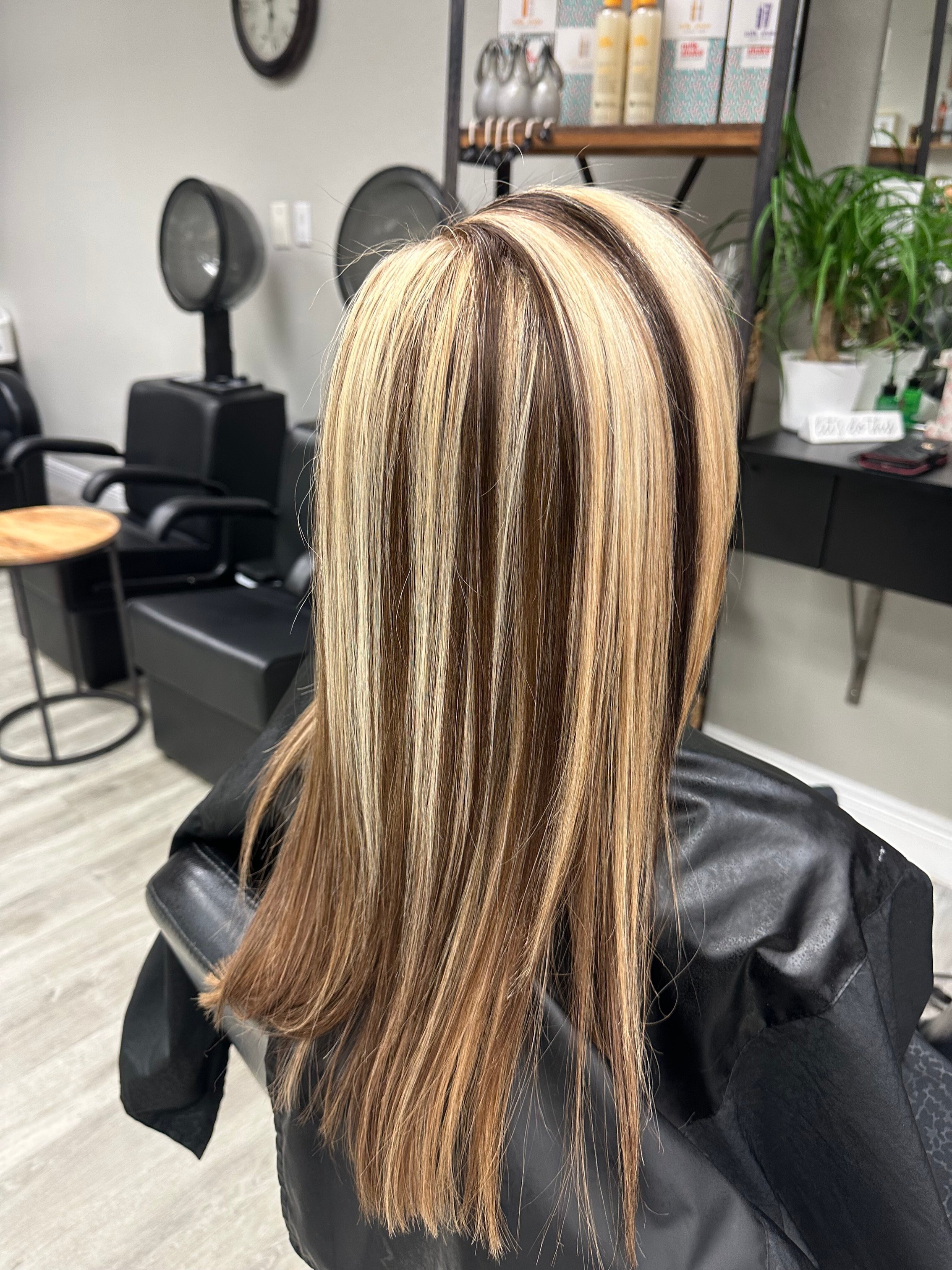“Freshly styled hair with blonde and dark highlights, showcasing a sleek and professional salon finish.”